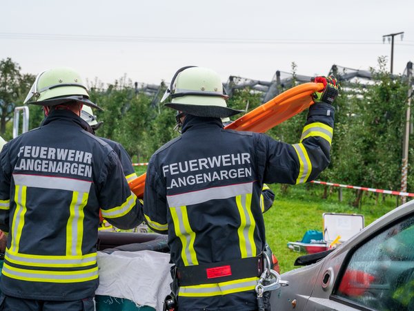 Zwei Kräfte der Feuerwehr Langenargen bringen ein Spineboard zum Einsatz, um eine Person aus einem PKW zu befreien.