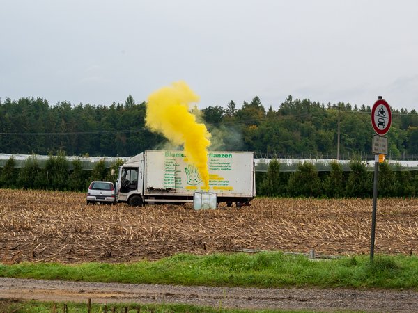 Verunfallter LKW und ein PKW stehen auf einem Feld. Aus einem Behälter des LKW tritt gelber Nebel aus.