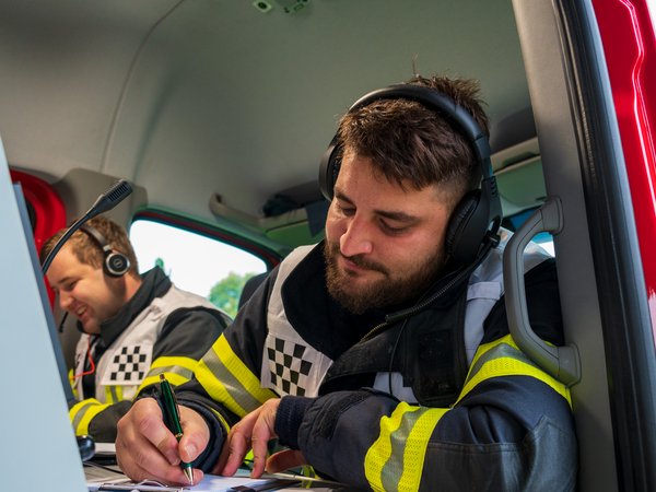 Zwei Führungsassistenten im Einsatzleitwagen wickeln Fungespräche mit Headsets ab und dokumentieren den Einsatzverlauf.